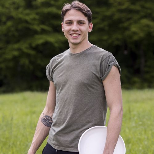 cheerful-young-male-standing-with-frisbee-nature